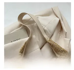 Gros plan détaillé sur la texture en paille tressée et la poignée en cuir crème du sac