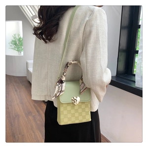 Detail of green and yellow checkerboard handbag with heart buckle and scarf handle