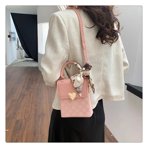 Detail of pink crossbody bag with gold heart lock and decorative printed silk scarf handle