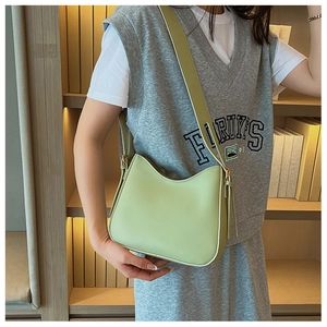 Détail du sac croissant vert menthe avec bandoulière large et gland sur un mannequin