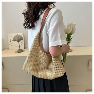 Détail d'un sac hobo en paille tissé main avec bandoulière en cuir marron sur modèle