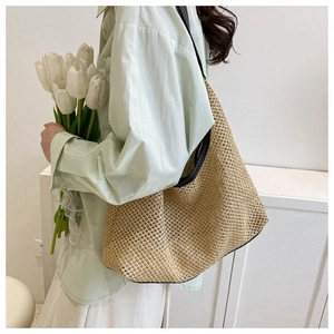 Détail d'un sac cabas en paille tressée avec des anses en cuir noir contrasté
