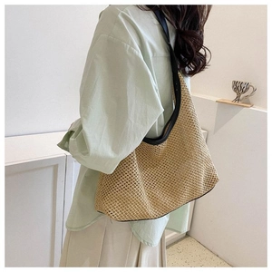 Détail du sac cabas en paille tissé avec bordure en cuir noir et texture naturelle sur modèle
