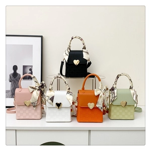 Close-up of mini crossbody bags with gold heart locks and elegant silk scarf handles