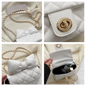 Detailansicht der weißen gesteppten Mini-Umhängetasche mit Schleife und Goldkette