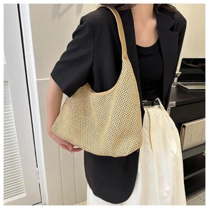 Détail du sac à bandoulière en paille tressée avec matière texturée beige sur un modèle