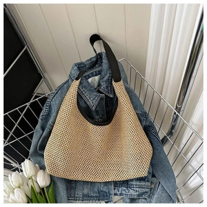 Détail du sac hobo en paille tissée avec bordure noire et grand espace intérieur