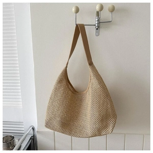 Détail d'un sac hobo en paille tressée montrant la texture et la large bandoulière