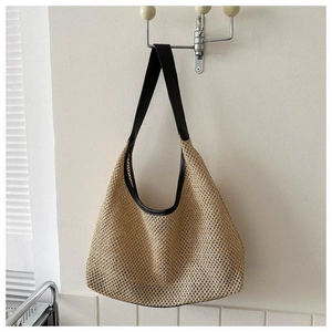 Détail du tissage en paille et de la bordure en cuir noir sur un sac porté épaule hobo