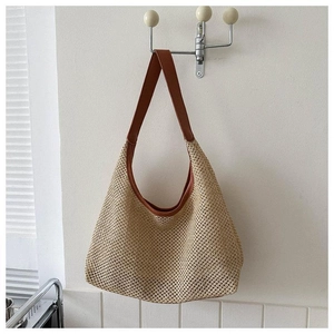 Détail du sac de plage en paille avec bordure en cuir marron et texture crochetée