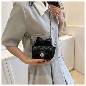 Detailaufnahme der schwarzen Stepptasche mit Schleife und Kettenriemen am Modell