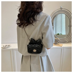 Schwarze gesteppte Mini-Umhängetasche mit Schleife und Goldkette am Model gezeigt