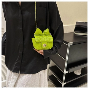 Nahaufnahme der hellgrünen gesteppten Minitasche mit Schleife und Goldkette am Modell