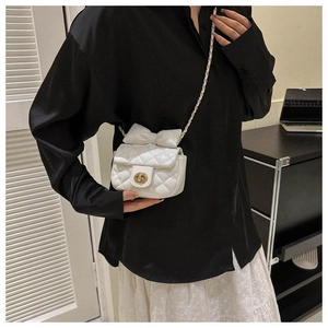 Detailansicht der kleinen weißen Stepptasche mit großer Schleife und goldener Kette