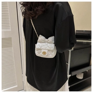 Detailansicht einer weißen gesteppten Mini-Umhängetasche mit Schleife und goldener Kette