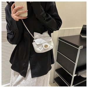 Detailansicht der weißen Mini-Stepptasche mit großer Schleife und goldener Kettenriemen