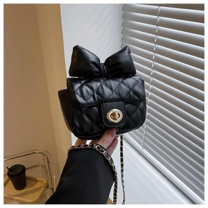 Detail einer schwarzen Stepptasche mit großer Schleife und klassischer Kette