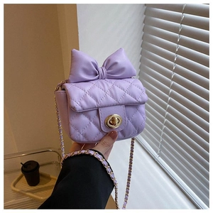 Detail der lila gesteppten Mini-Tasche mit großer Schleife und goldener Kette