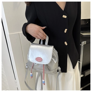 Gros plan du mini sac à dos argenté avec cordons roses et détails de perles