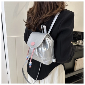 Détail du mini sac à dos argenté avec cordon rose et perles décoratives au dos