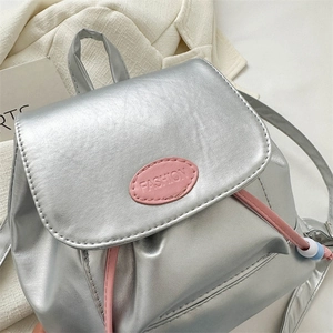 Détail d'un sac à dos argenté avec cordon rose et rabat embossé du mot FASHION