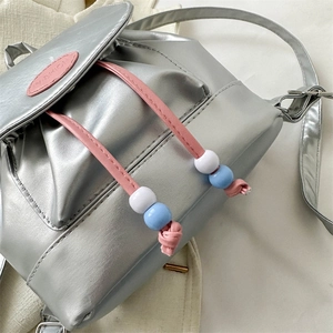 Vue détaillée d'un mini sac argenté avec cordon rose et détails de perles