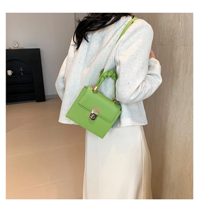 Close-up of green matte PU leather crossbody bag with pleated handle and gold twist lock