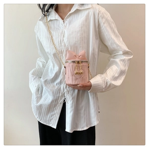Détail du mini sac seau rose matelassé avec nœud décoratif et chaîne dorée