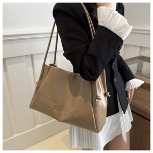Close-up of embossed lettering and side drawstring knot detail on khaki tote bag