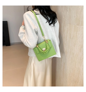 Model wearing fluorescent green crossbody bag with gold buckle and pleated handle
