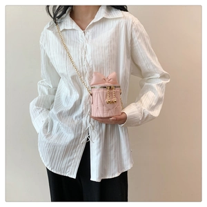 Détail du mini sac cylindre rose matelassé avec nœud et bandoulière chaîne dorée