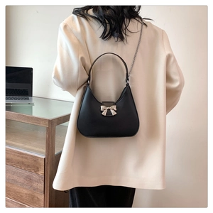Détail du sac hobo noir avec boucle en nœud argenté et bandoulière chaîne en métal chic