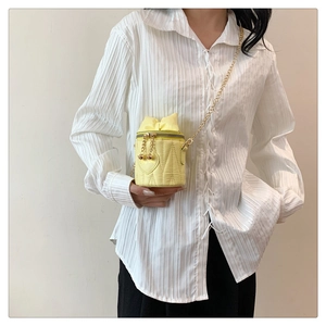 Détail du sac seau cylindrique jaune matelassé avec surpiqûres cœur et bandoulière chaîne