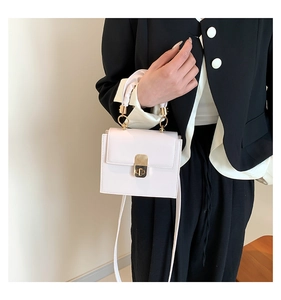 Cream white rectangular crossbody bag featuring elegant gold twist lock and metal handle