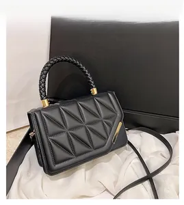 Détail du petit sac carré noir matelassé avec poignée tressée et boucles dorées