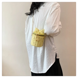 Sac seau jaune pâle avec nœud matelassé porté pour illustrer le style et la taille
