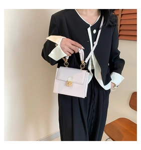 Close-up of beige square crossbody bag with gold lock and silk scarf wrapped handle