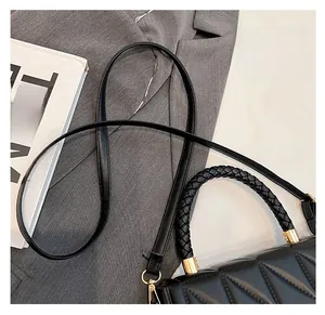Gros plan du sac bandoulière en cuir noir avec poignée tressée et texture géométrique