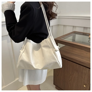 Detail of white leather tote bag with embossed letters on a stylish model's shoulder