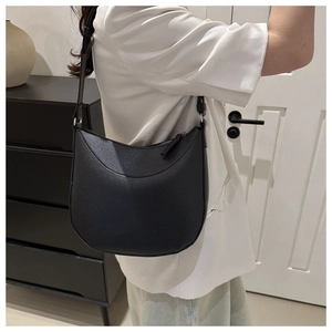 Detail of black pebbled leather crescent bag with adjustable strap and silver zipper