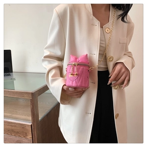 Détail du sac seau rose matelassé avec nœud papillon géant et bandoulière dorée