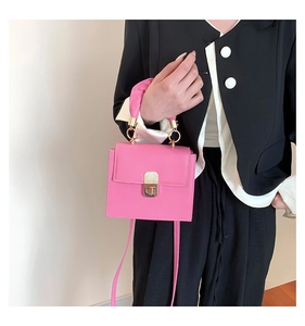 Detail of pink square crossbody bag featuring a golden lock and smooth leather texture