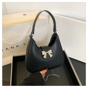 Dettaglio di una borsa hobo nera con fibbia a fiocco d'argento e catena in metallo elegante