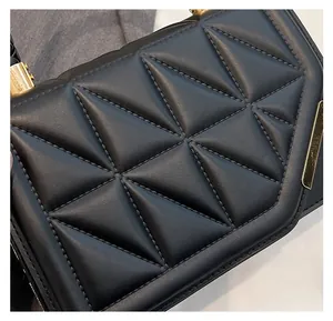 Gros plan détaillé du matelassage géométrique 3D en cuir noir et des ferrures dorées du sac