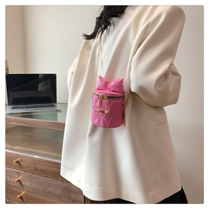 Détail du mini sac seau rose avec nœud surdimensionné et surpiqûres cœurs dorées