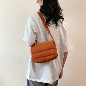 Quilted orange puffer crossbody bag with wide shoulder strap for casual spring outfits