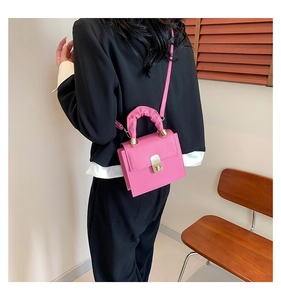 Fashionable pink mini square bag with pleated handle and gold lock on black blazer