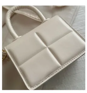 Macro view of cream quilted PU leather texture and gold metal D-ring on mini handbag