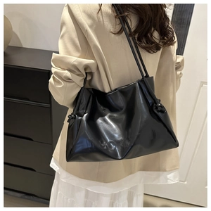 Detail of black glossy faux leather tote bag with pleated top and knotted shoulder strap