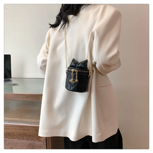 Détail du mini sac seau noir avec nœud décoratif, surpiqûre cœur et chaîne dorée